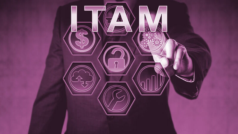 Körper eines Geschäftsmanns, der mit seinem Finger auf die Buchstaben ITAM und weitere Symbole zeigt.